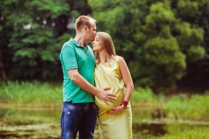 Engagement pregnant woman is being kissed by her husband