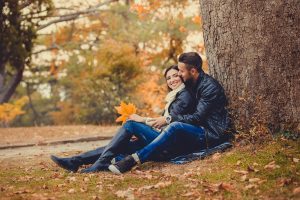Engagement couple smiling under a tree during fall