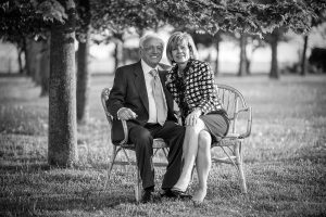 happy couple late 60s smiling on a bench in the parlk