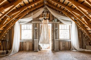 bride dress hanging in a barn backlit